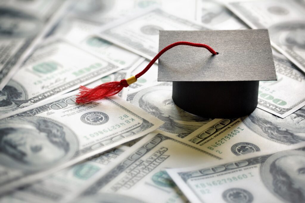 A graduation cap sitting on top of money.