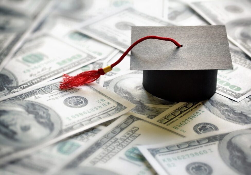 A graduation cap sitting on top of money.